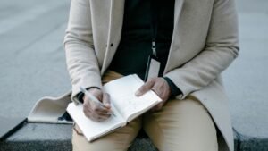 A person writing on a notebook on his lap