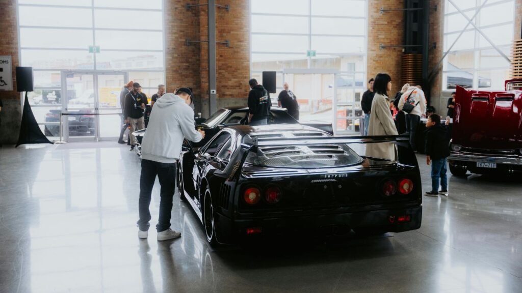 a cinfused person lookin at the cars in a car show room while other customers are busy examining a car.