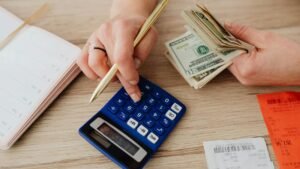 A hand using a calculator and some cash on the other hand